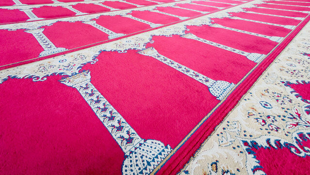 Patterned red prayer carpets arranged across mosque floor