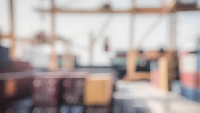 A blurred view of a shipping yard with containers stacked and a vague industrial background, conveying a sense of logistics and transport.