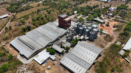 Industrial food processing plant with metal storage silos surrounded by rural landscape © Salsabila Ariadina