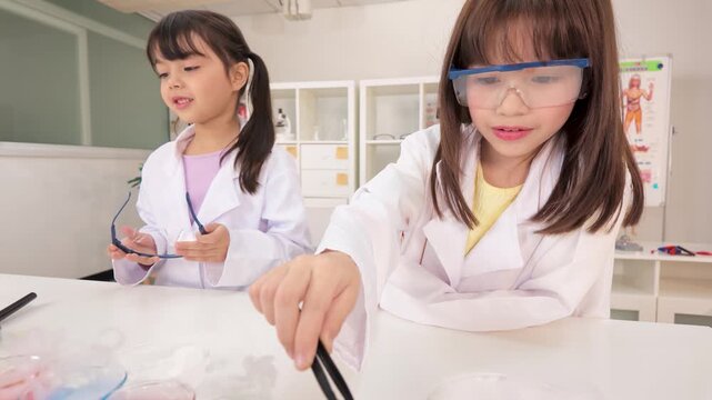 Two Young Schoolgirls Conducting Chemistry Experiment in Classroom Laboratory