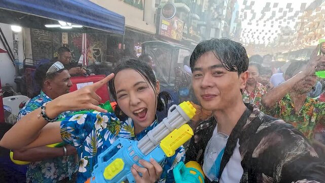 Asian Couple Having Fun with Water Guns During Songkran Water Festival