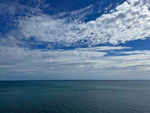 Blue ocean under a dramatic cloudy sky on a sunny day.
