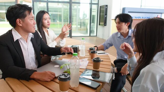 Asian Business Team Discussing Project Strategy Around Table in Bright Office