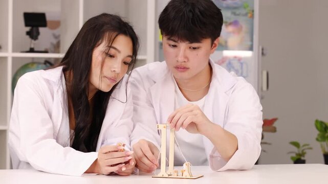 Asian Students in Lab Coats Building Wooden Physics Model