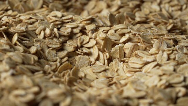 Dry oat flakes background, close up, rotation. Uncooked raw oat flakes grains. Healthy breakfast and diet eating ingredients for making oatmeal porridge. Gastronomy concept, organic food