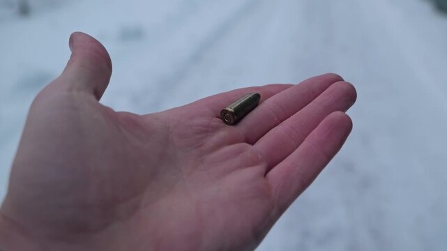 Single cartridge in open hand symbolizes Baltic deterrence and winter readiness