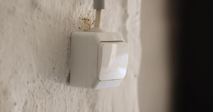 Close-up view of a white plastic wall switch is flipped off in controlling a garage door to close in a garage room interior.