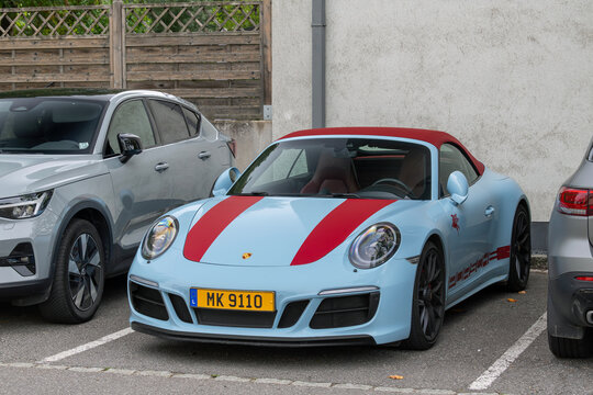 Mondorf-les-Bains, Luxembourg - September 13th 2026 : View on a blue Porsche 991 Carrera 4 GTS Cabriolet MkII parked on a street between cars.