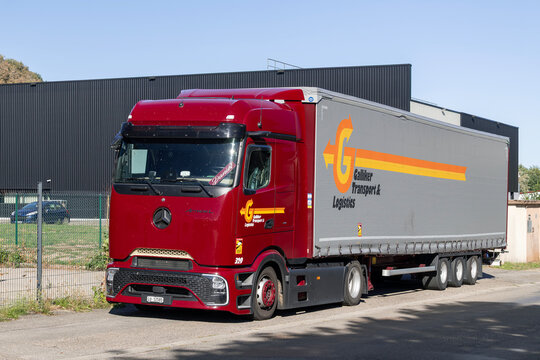 Munster, France - September 4th 2026 : View on a red truck Mercedes-Benz Actros L with a grey trailer parked in on a street for a delivery with an industrial building in the background.