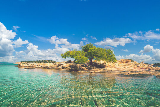 Seascape on a sunny day. Quiet bay with a small rocky island and sandy beach. beautiful lagoon. Lagonisi beach, Halkidiki, Greece