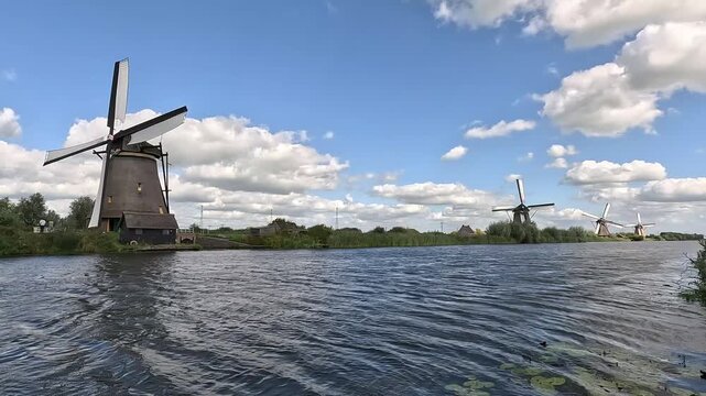 Traditional running Dutch windmills with turning sails along a canal in Kinderdijk, Netherlands