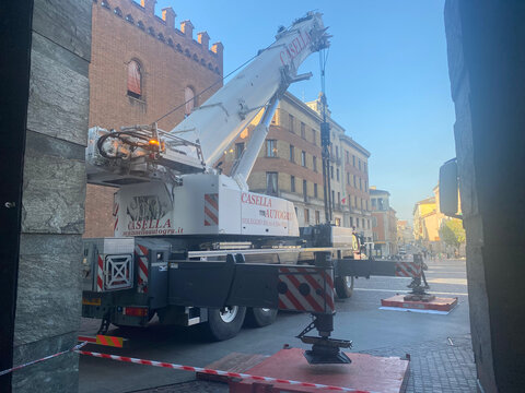 Large mobile crane with outriggers extended on Via Cesare Battisti, Cremona, addressing extensive damage from a severe hailstorm