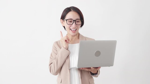 ノートパソコンを使う眼鏡をかけたスーツ姿の女性