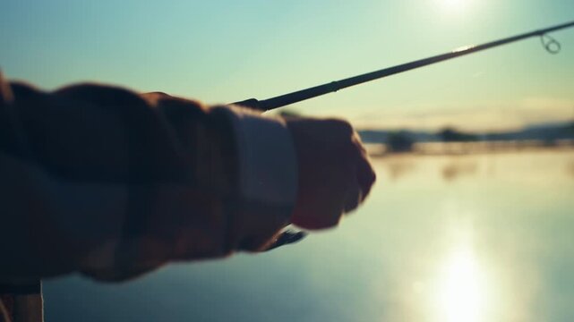 Close up female hands reeling a spinning rod during peaceful sunrise fishing on a tranquil lake capturing the perfect outdoor lifestyle and nature experience