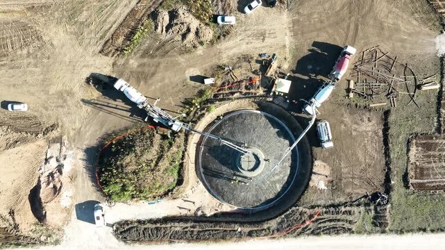 Aerial View of Concrete Pouring at Construction Site for Wind Turbine Foundation, Pump Trucks and Workers Building Renewable Energy Infrastructure