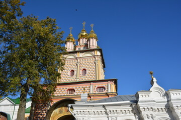 Church tower with golden domes under blue sky in a town © Alexander