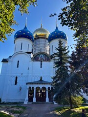 Colorful domes of a church stand tall against a blue sky on a sunny day in a park setting © Alexander