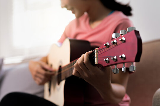 woman playing music with acoustic guitar at home