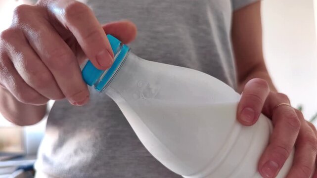 Woman closing a bottle of fresh milk on the kitchen table at home