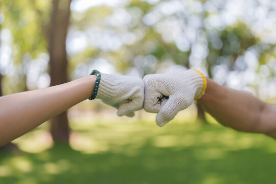 Volunteers doing fist bump in park for community teamwork and solidarity