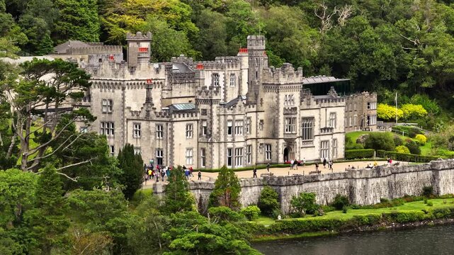 Kylemore Abbey in Letterfrack, Ireland, is a lakeside cultural landmark with Gothic Revival architecture, castellated walls, turrets and wooded hills.