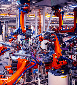Automated robotic arms working in a modern automobile manufacturing plant.