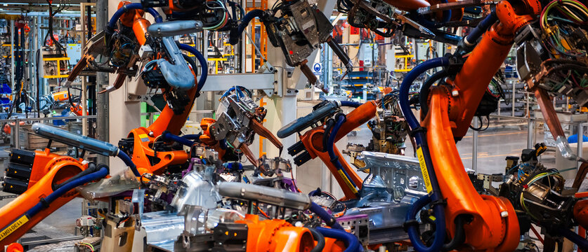 Automated robotic arms working in a modern automobile manufacturing plant.