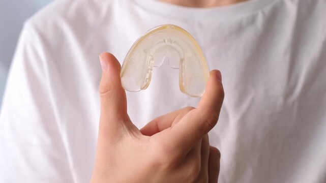 A person holds a clear dental aligner in their fingers. Orthodontic treatment, dental care, oral hygiene. High quality 4k footage.