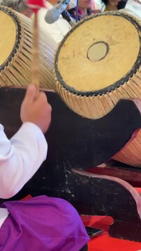 Vertical 4K video showing musician using wooden beaters to play traditional large Klong Thad barrel drum during performance.