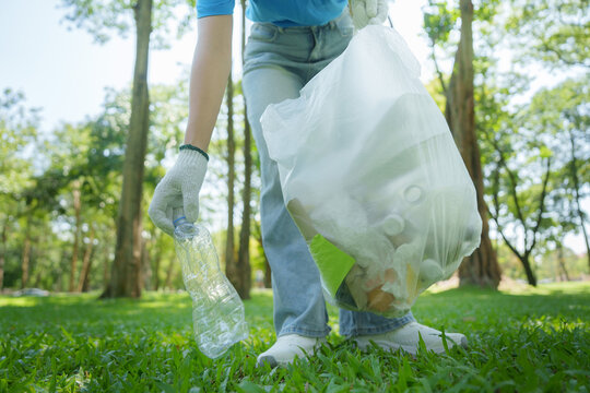 Volunteer picking up plastic bottle from grass for environmental protection