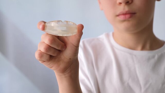 A Child holds a clear dental aligner in their fingers. Orthodontic treatment, dental care, oral hygiene. High quality 4k footage.