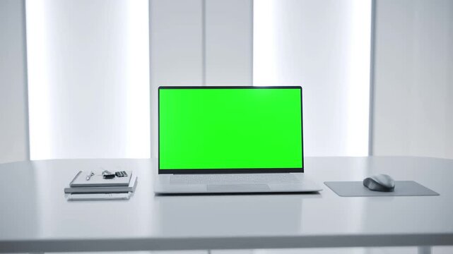 Laptop with Green Screen on White Desk in Modern Clean Tech Lab Interior