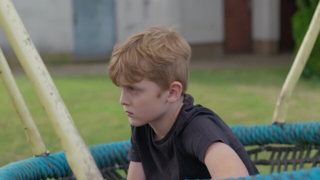 The serious boy is swinging on a swing slow motion focus transition from blur to sharpness