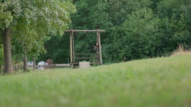 The boy jump on a zip line rope swing low angle outdoors