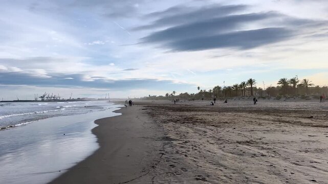 People on a sunny winter day actively relax with their families. A day off on the beach of the Mediterranean Sea in winter. Grao. Castellon de la Plana. Valencia. Spain