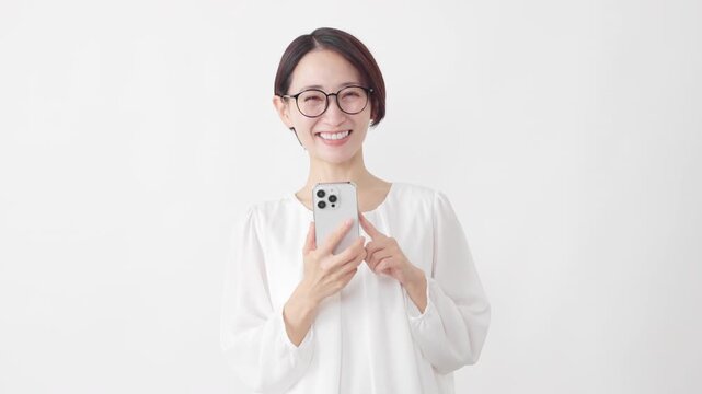 スマートフォンを使うメガネをかけたカットソー姿の女性　ライフスタイルイメージ