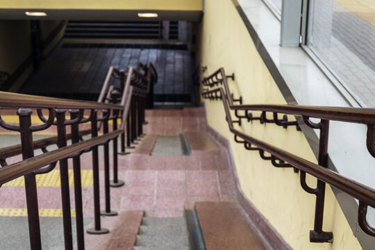 High angle view of outdoor concrete staircase with metal handrails leading down to pedestrian underpass