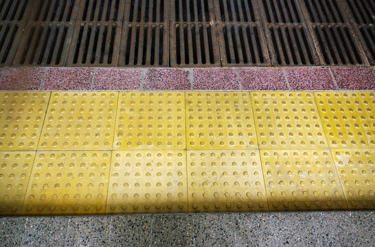 Top view of yellow tactile paving tiles with drainage grid providing barrier free environment for visually impaired