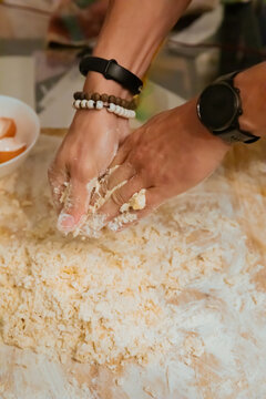 Top view of hands kneading pasta dough with flour