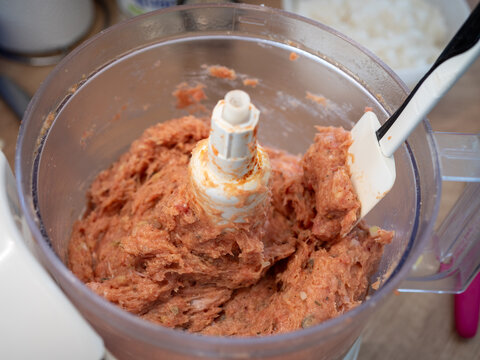 Ground pork shoulder mixed in a food processor with visible seasoning, prepared as a raw meat mixture for homemade cooking and meat recipes.