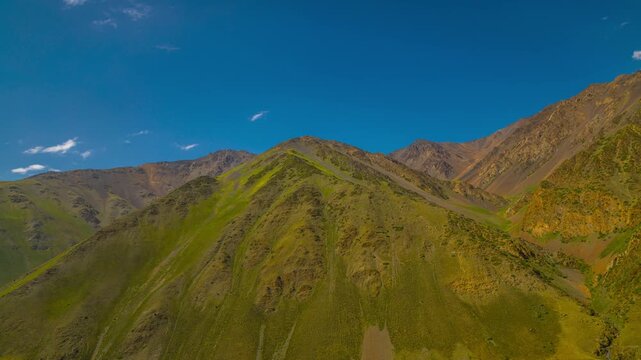 Time lapse of white clouds flowing over top of Kyrgyzstan mountains forming shadows