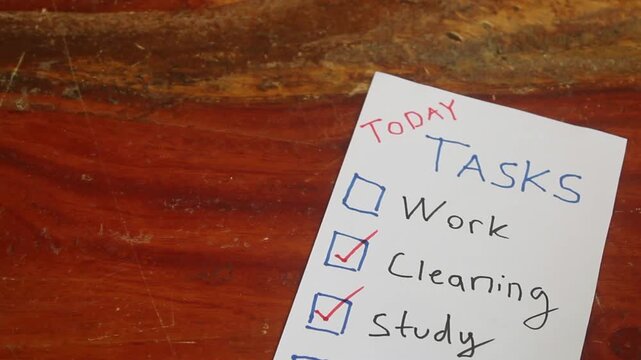 Close-up of a hand checking off completed tasks on a handwritten to-do list, illustrating daily planning, productivity, organization, and everyday work and household routines.