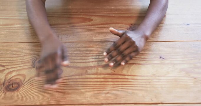 Close up of people talking to the camera, hands resting on wooden table, person contemplating or wai