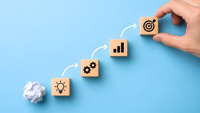 Hand placing the final target block on a staircase showing business strategy process starting from a crumpled paper idea