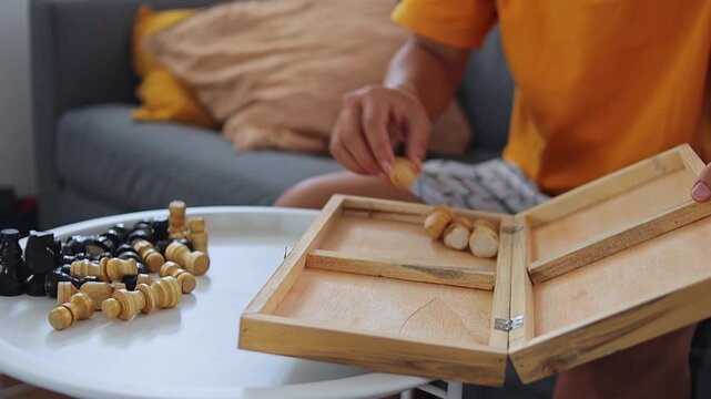 Close-up of hands storing chess pieces inside wooden case
