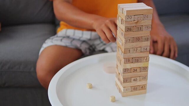 Close-up of hands rolling dice and pulling numbered wooden block from stacking tower