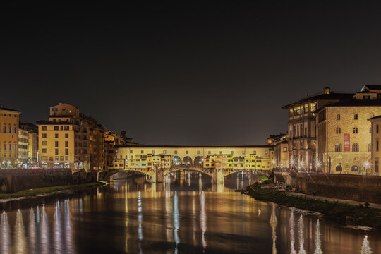 View of the illuminated Ponte Vecchio bridge spanning the Arno River at night in Florence, Tuscany, Italy.
