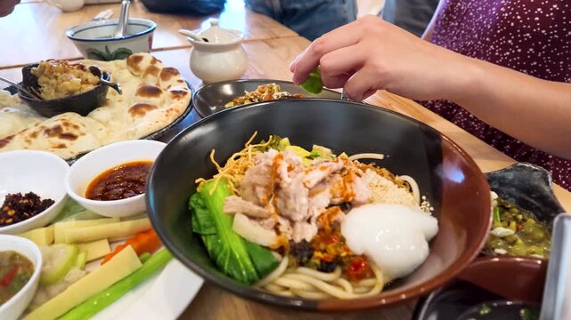 Person Squeezing Fresh Lime Over Burmese Mee Shay Noodle Bowl