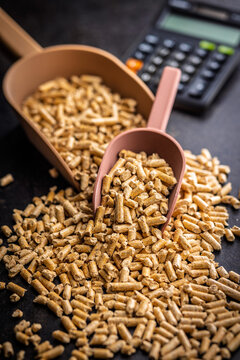 Wood Pellets Fuel Pile With Plastic Scoops and Calculator for Biomass Heating and Energy Costing