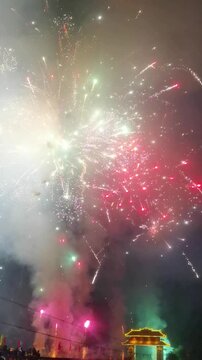 Vertical Video: Handheld smartphone shot of fireworks and firecrackers during a rural Chinese New Year celebration.